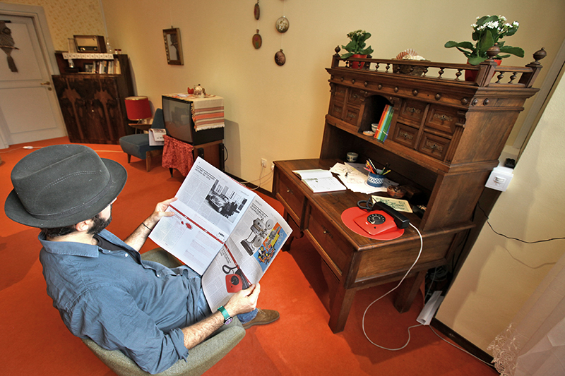 A visitor in the living room with the exhibition guide.